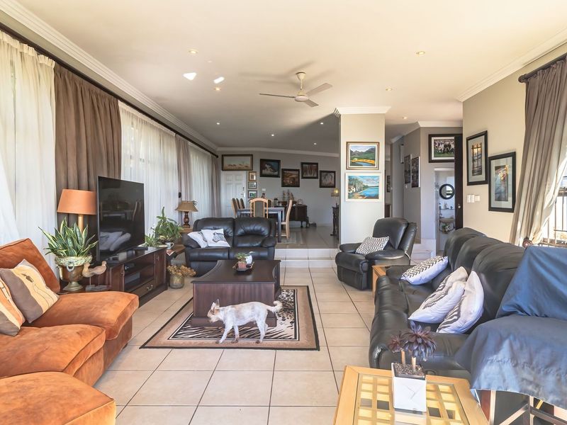 Spacious open-plan living and dining area featuring tiled flooring, recessed lighting, a ceiling fan, and large windows providing ample natural light.
