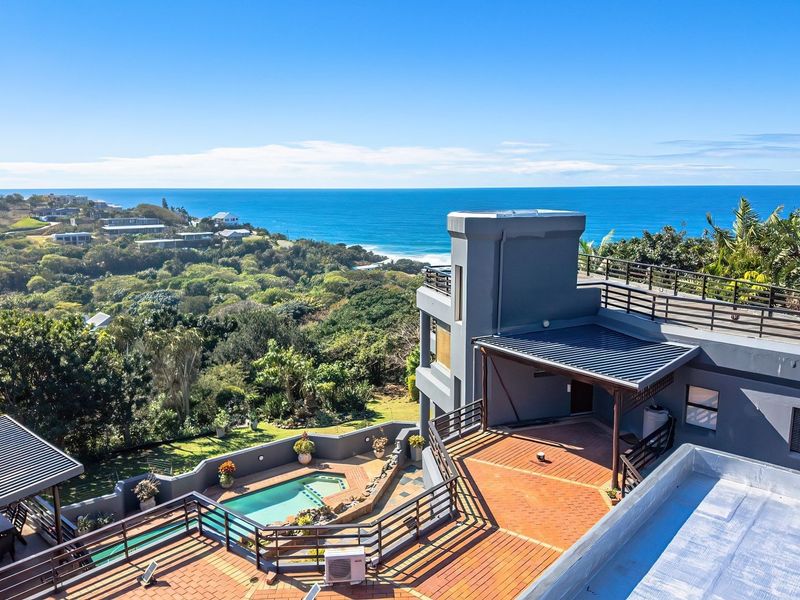 Aerial view of a multi-level property featuring a swimming pool, expansive tiled terraces, and panoramic ocean views.