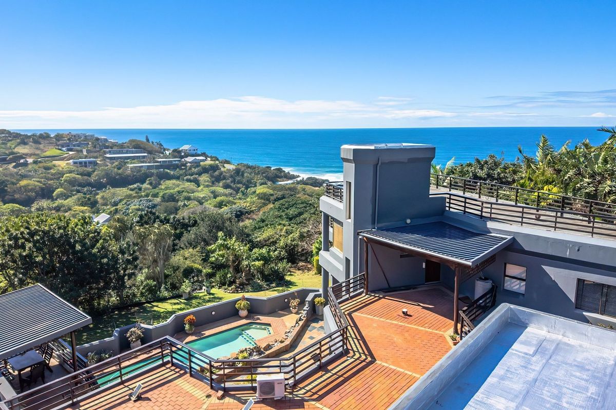 Aerial view of a multi-level property featuring a swimming pool, expansive tiled terraces, and panoramic ocean views.