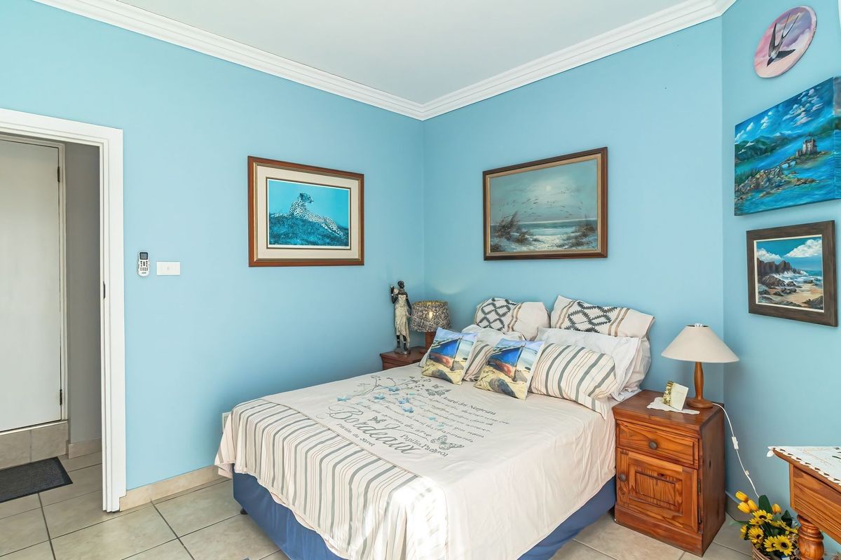 A bedroom featuring light blue walls, crown molding, tiled flooring, and a wall-mounted split system air conditioner.