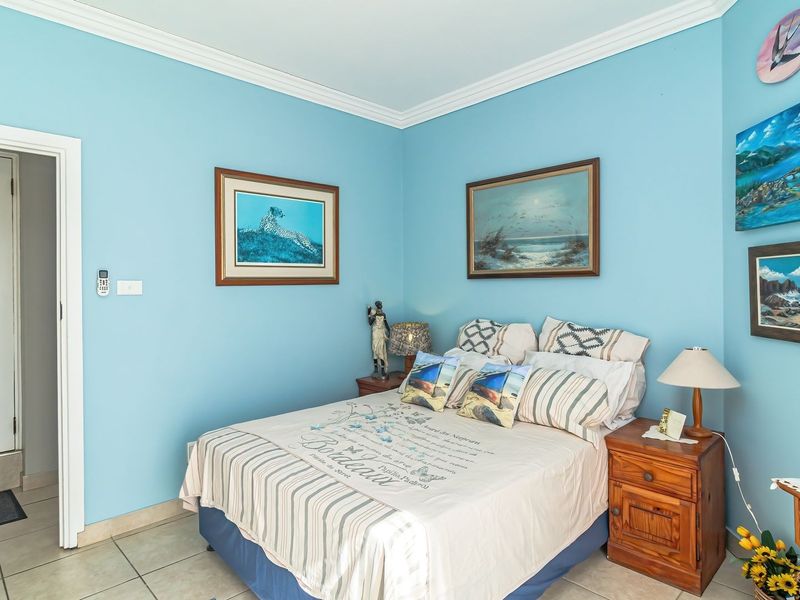 A bedroom featuring light blue walls, crown molding, tiled flooring, and a wall-mounted split system air conditioner.