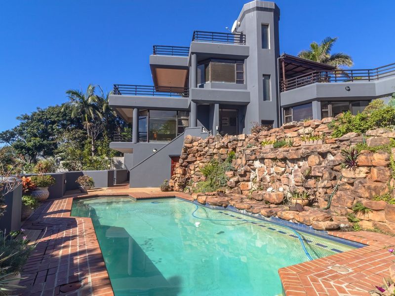 Multi-level residential property featuring a swimming pool, stone retaining wall, and multiple balconies with exterior access.