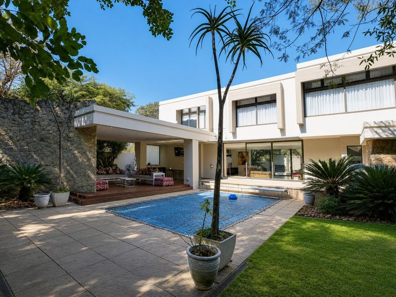 Spacious rear exterior featuring a covered patio, swimming pool with safety cover, stone feature wall, and modern architectural design with large sliding glass doors.
