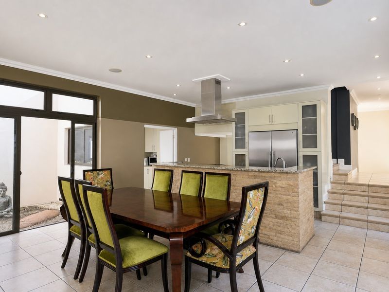 Open plan dining and kitchen area featuring a stone-topped island, modern cabinetry, tiled floors, and direct access to an outdoor patio area.