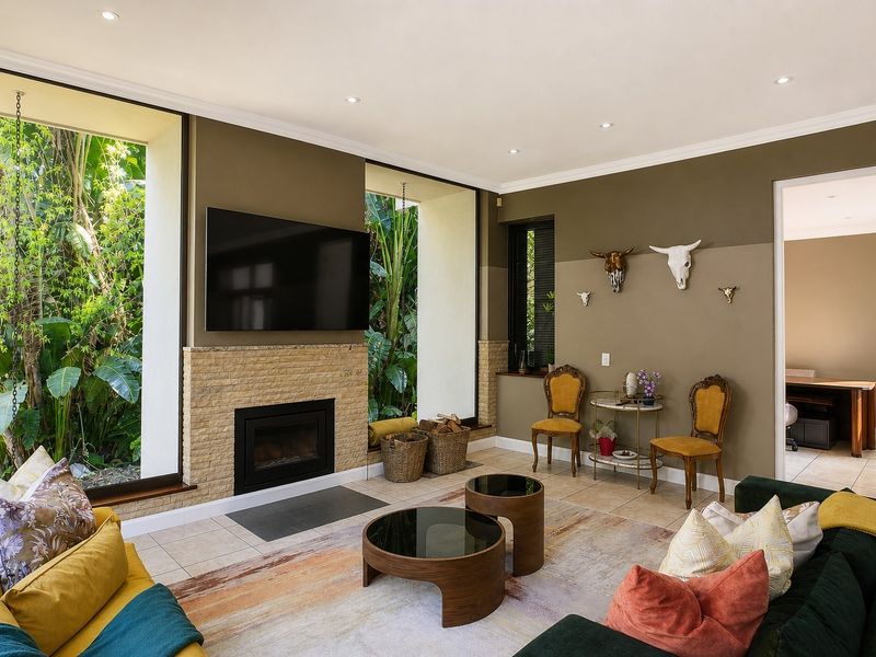 Spacious living room featuring a stone-surround fireplace, large floor-to-ceiling windows with garden views, and neutral tiled flooring.