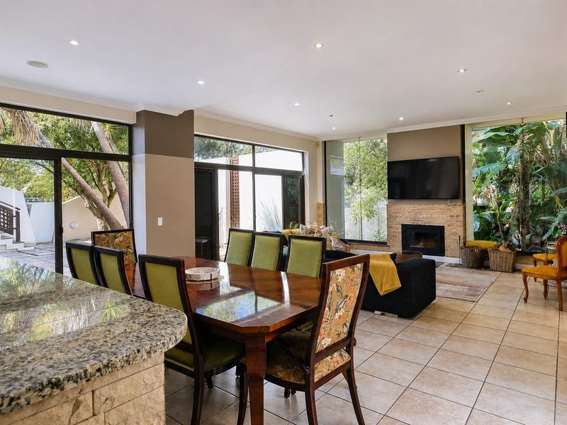 Spacious open-plan living and dining area featuring tiled floors, a stone-clad fireplace, and large sliding doors providing seamless access to the outdoor garden space.