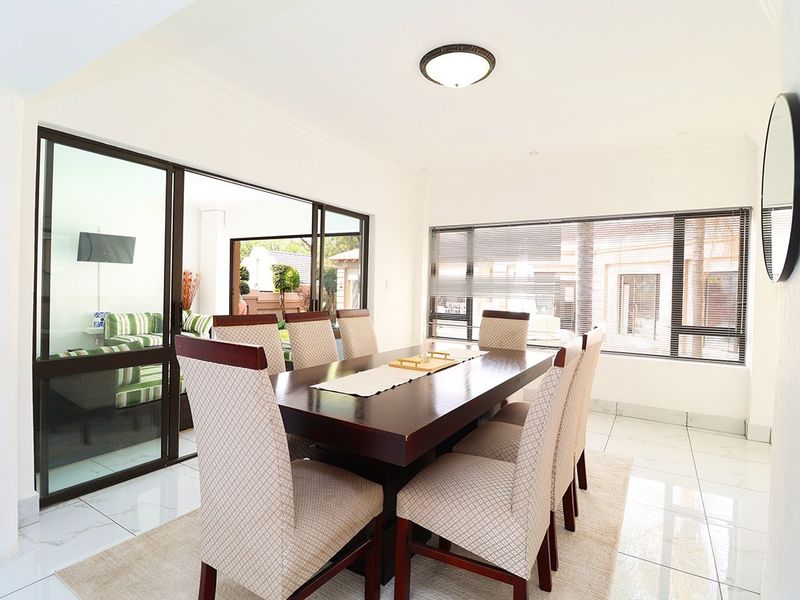 Bright dining room featuring polished tiled flooring, large sliding glass doors providing outdoor access, and modern aluminium window frames.