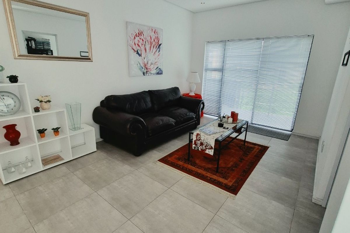 A bright living room featuring large format floor tiles, recessed downlighting, and venetian blinds, offering a clean and neutral foundation for modern living.