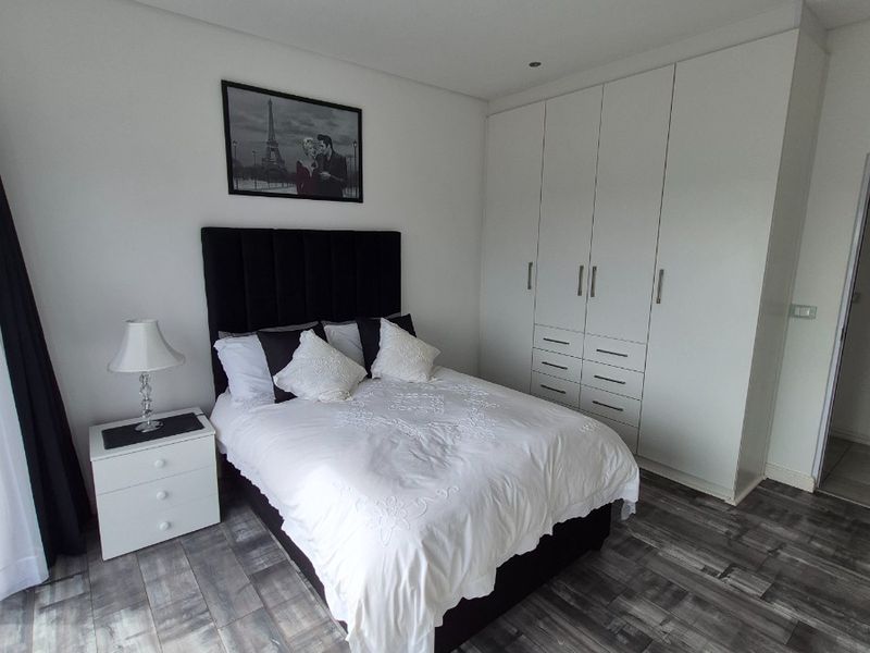 A well-maintained bedroom featuring modern laminate flooring, recessed downlighting, and ample built-in cupboard storage.