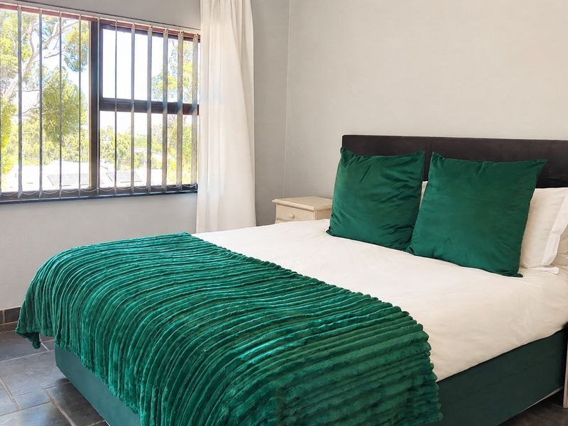 A bedroom featuring tiled flooring and a window fitted with security bars, providing natural light and a view of the surrounding area.