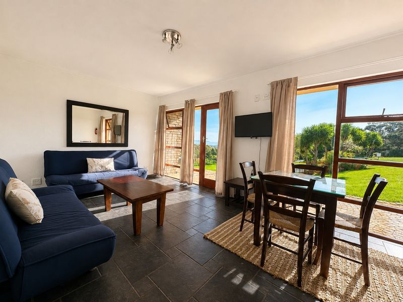 Open plan living and dining area featuring dark tiled flooring and large glass doors providing natural light and access to the garden.