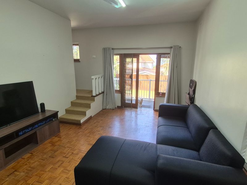 Living room featuring parquet flooring, a staircase, and a sliding glass door providing access to an outdoor area.