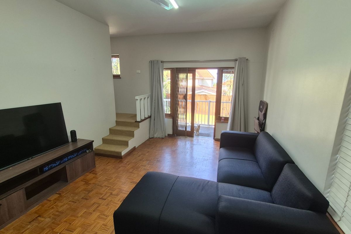 Living room featuring parquet flooring, a staircase, and a sliding glass door providing access to an outdoor area.