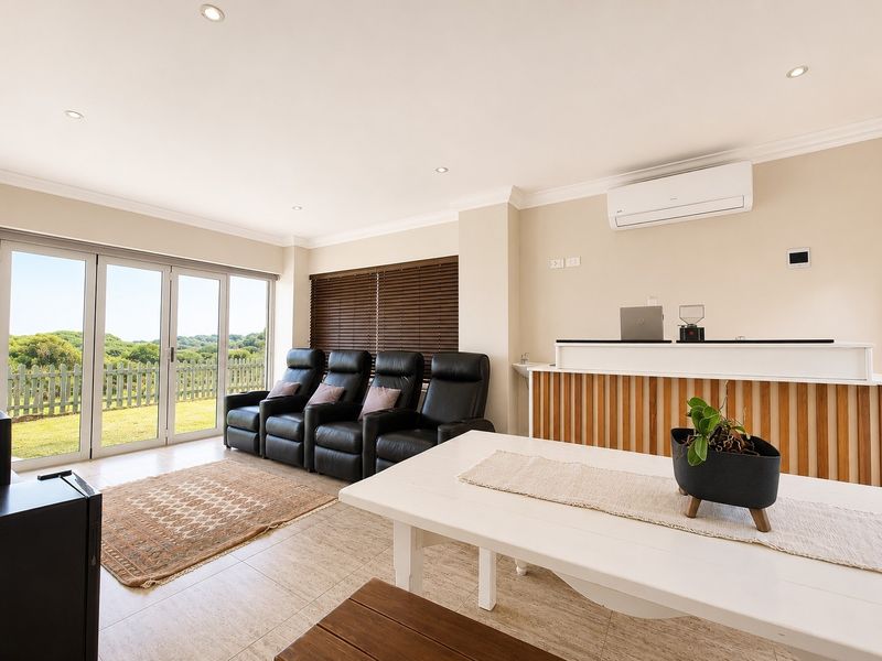 Spacious living area featuring tiled floors, recessed lighting, a split-system air conditioner, and a built-in bar, with direct access to the outdoor garden area.