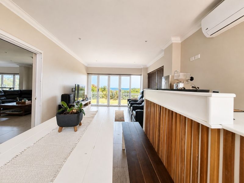 Spacious open-plan living area featuring a timber-accented breakfast bar, air conditioning, and large sliding doors opening to a scenic outdoor view.