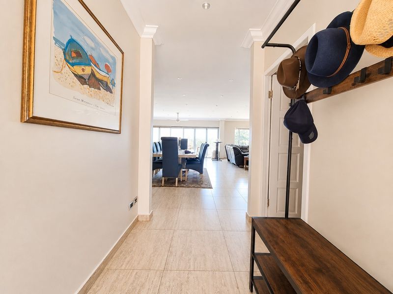 A bright, tiled entrance hallway leading into an open-plan living and dining area with neutral finishes and recessed lighting.