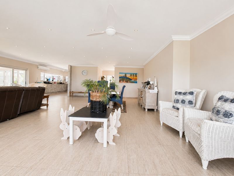 Spacious open-plan living and dining area featuring neutral tiled flooring, recessed lighting, a ceiling fan, and direct access to the outdoor patio.