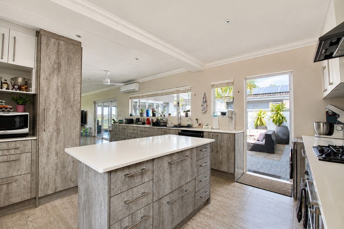 Modern kitchen featuring wood-grain cabinetry, stone countertops, a central island, and direct access to an outdoor patio area.