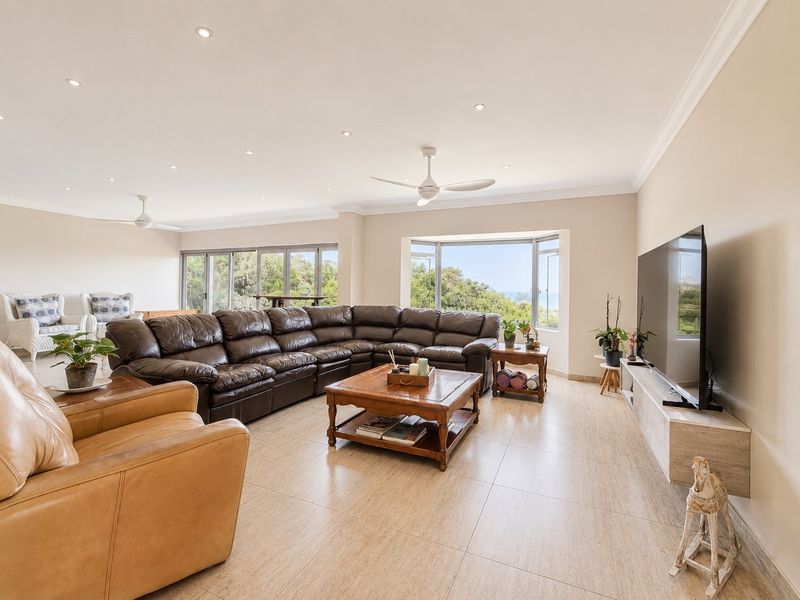 Spacious living room featuring tiled flooring, recessed lighting, ceiling fans, and large windows with natural light and scenic views.