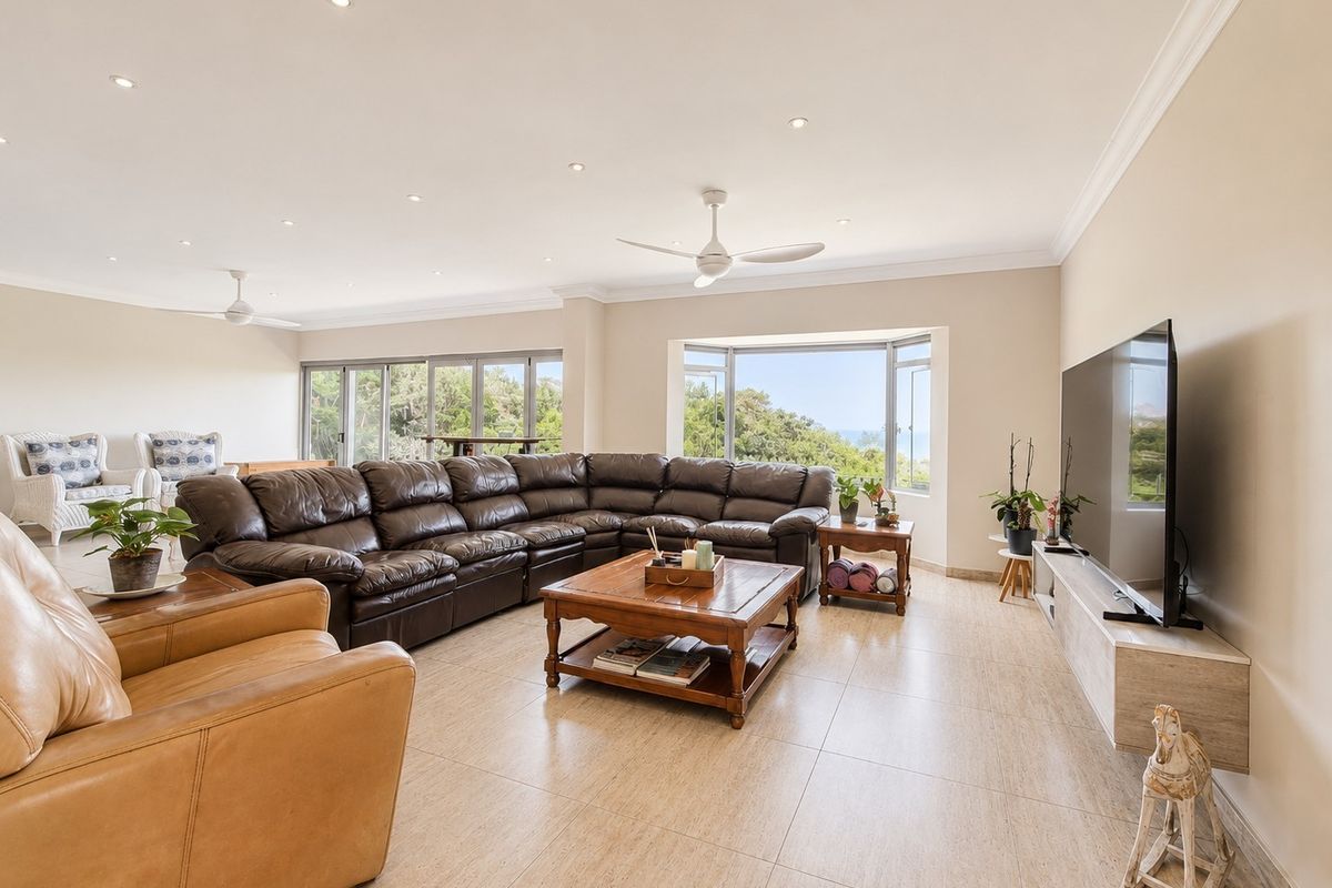 Spacious living room featuring tiled flooring, recessed lighting, ceiling fans, and large windows with natural light and scenic views.