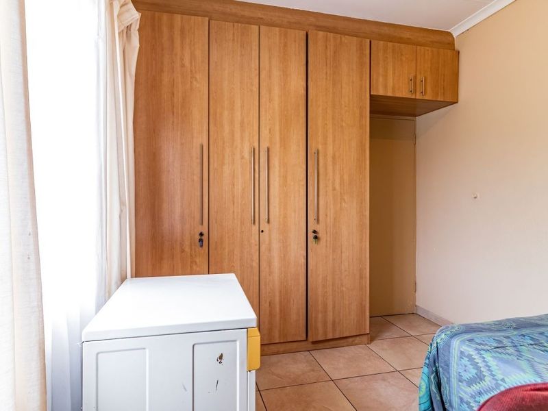 A bedroom featuring built-in wooden cupboards and tiled flooring, providing functional storage space within the apartment.
