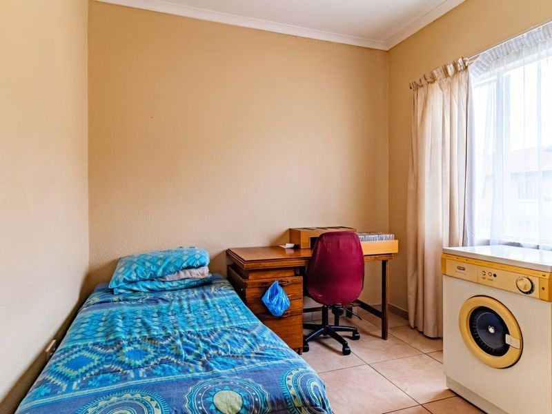 A functional bedroom space featuring tiled flooring and a built-in washing machine, offering versatile utility within the apartment layout.