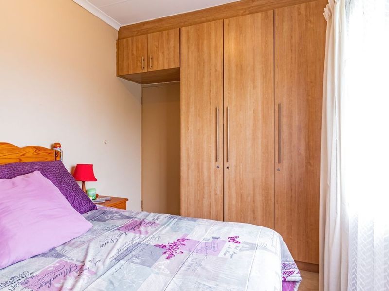 A bedroom featuring light wood-finish built-in cupboards with ample storage space and neutral wall tones.