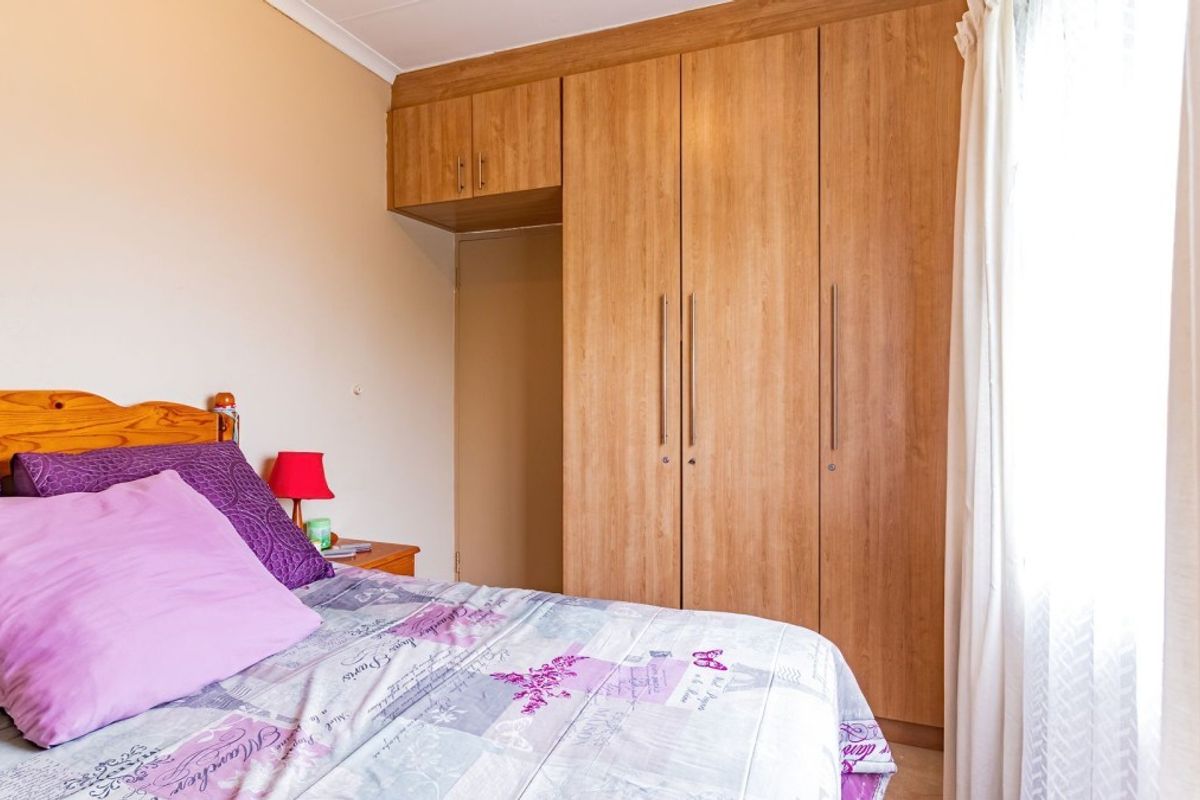 A bedroom featuring light wood-finish built-in cupboards with ample storage space and neutral wall tones.
