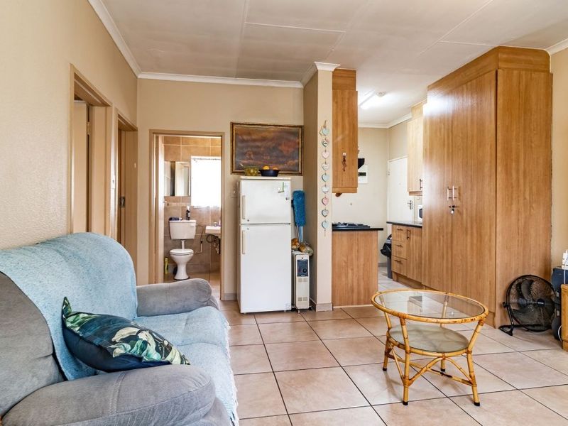 Open-plan living area featuring tiled flooring, built-in kitchen cabinetry, and integrated storage cupboards, with direct access to an adjacent bathroom.