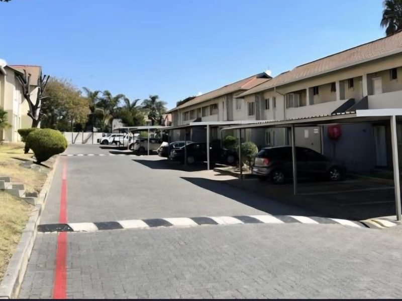 Exterior view of the apartment complex parking area featuring covered carports and paved driveway access.