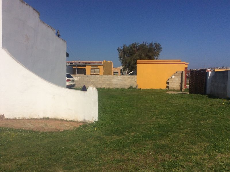 A spacious backyard area featuring a lawn and perimeter boundary walls, offering potential for landscaping or outdoor development.
