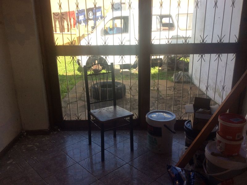 An interior living space featuring tiled flooring and a security gate, currently in need of maintenance and cosmetic updates.