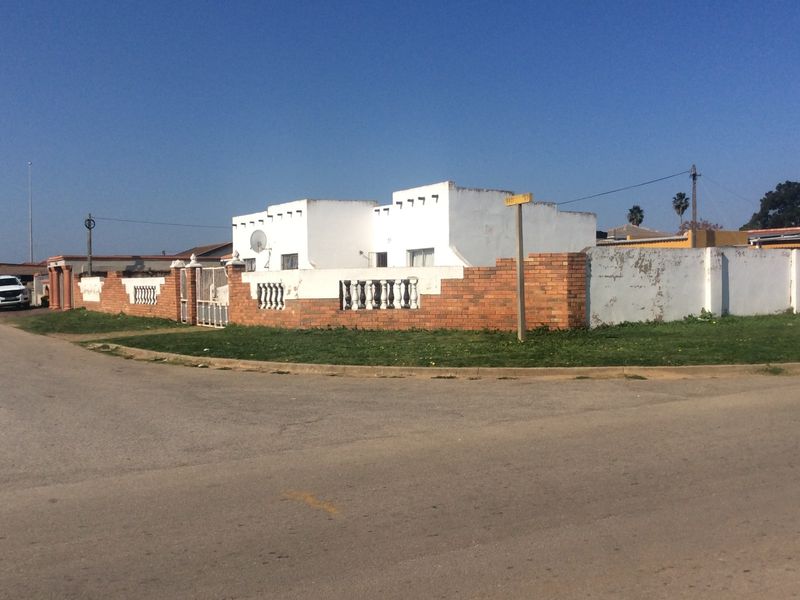 Street view of a residential property featuring a brick boundary wall with concrete balustrades and a white rendered facade.