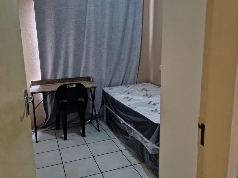 A compact bedroom featuring tiled flooring, viewed from the doorway.