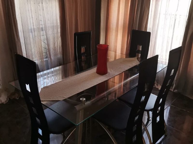 A dining area featuring dark tiled flooring and large windows with curtains, providing a functional space for meals.