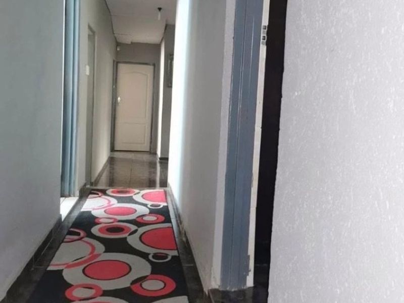 A narrow residential hallway featuring tiled flooring and multiple internal access points, providing a functional transition space between rooms.