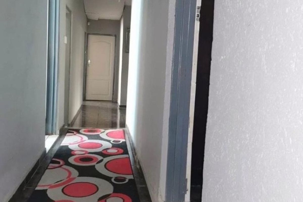 A narrow residential hallway featuring tiled flooring and multiple internal access points, providing a functional transition space between rooms.
