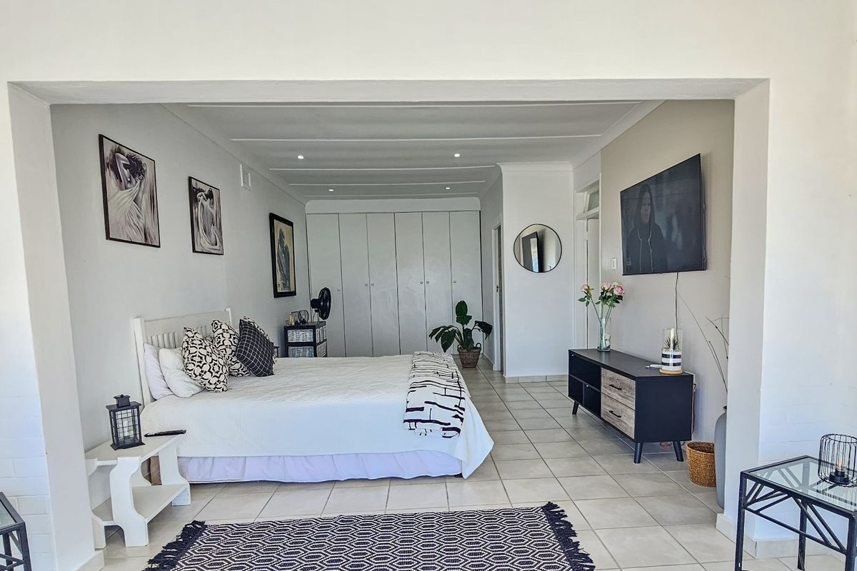 Spacious bedroom featuring neutral tiled flooring, recessed ceiling lighting, and extensive built-in cupboard storage.