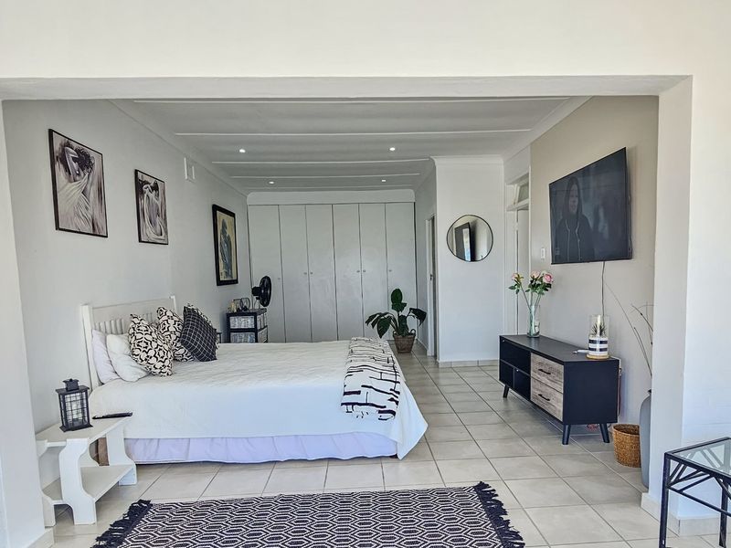 Spacious bedroom featuring neutral tiled flooring, recessed ceiling lighting, and extensive built-in cupboard storage.