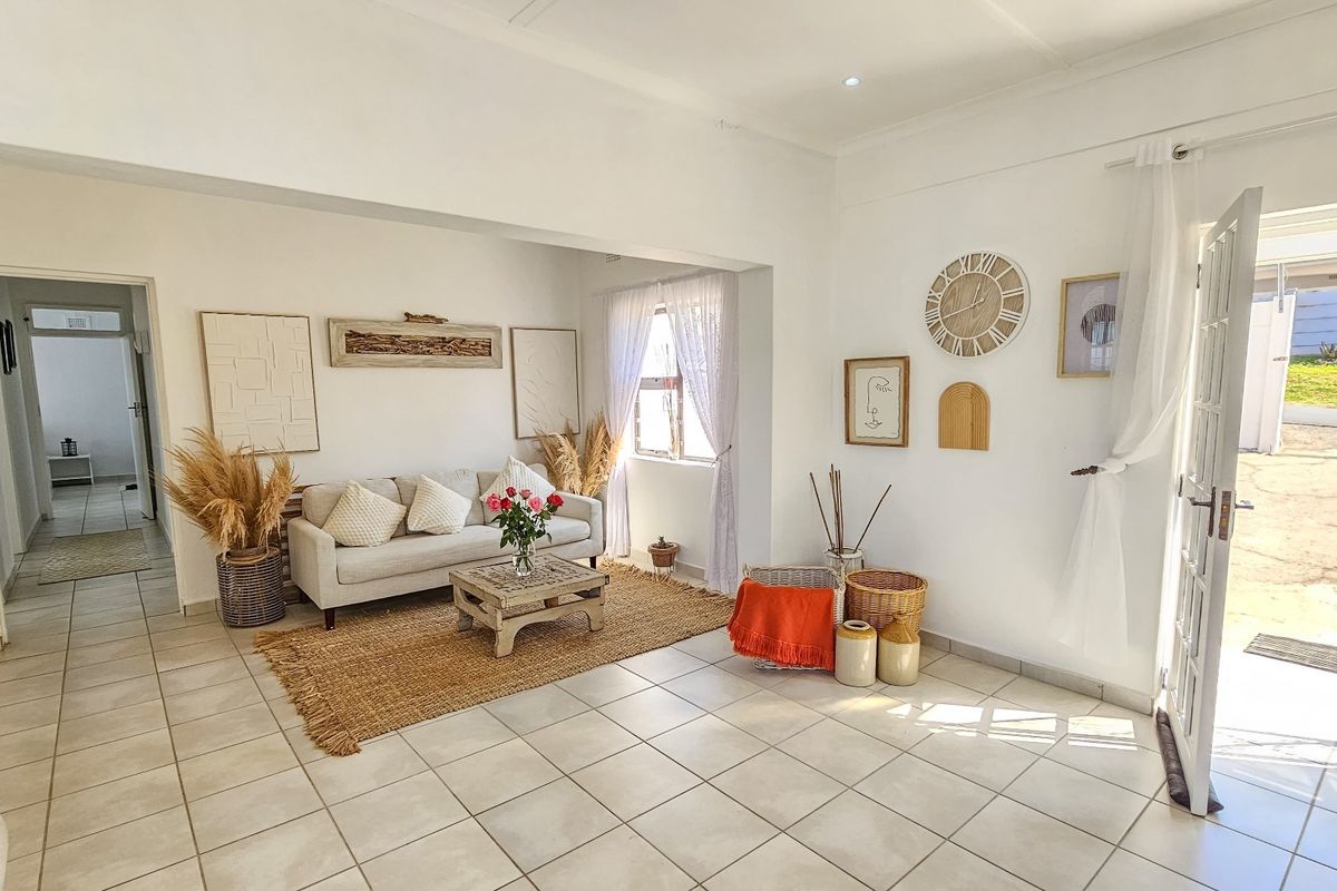 A bright and airy living room featuring neutral tiled flooring, recessed lighting, and direct access to the exterior through a glass-paneled door.