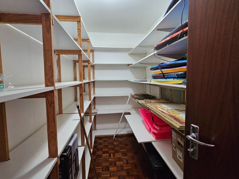A functional storage room or pantry featuring extensive built-in shelving and classic parquet flooring, providing ample space for organization.