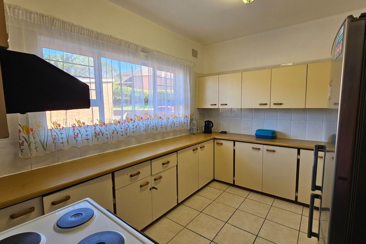 A functional kitchen featuring tiled flooring, laminate countertops, and ample built-in cabinetry, offering a practical layout with a classic design.