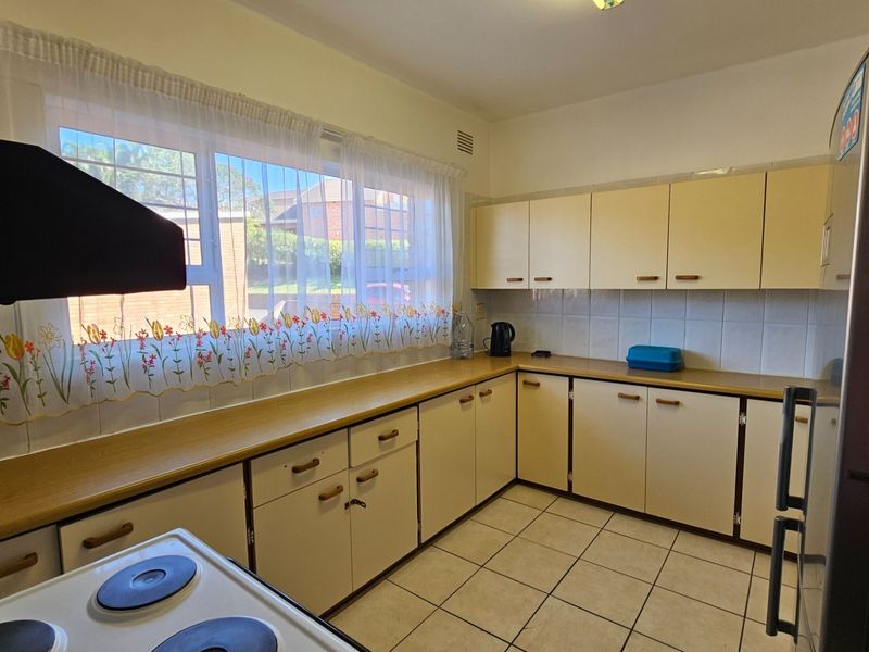 A functional kitchen featuring tiled flooring, laminate countertops, and ample built-in cabinetry, offering a practical layout with a classic design.
