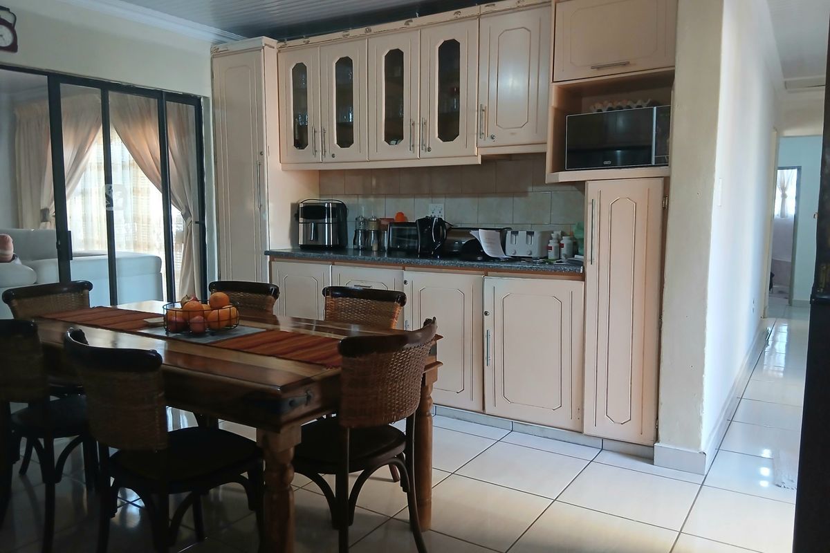 A functional kitchen area featuring built-in cabinetry, tiled flooring, and direct access to an outdoor space through sliding glass doors.