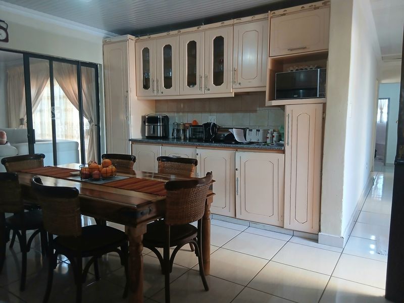 A functional kitchen area featuring built-in cabinetry, tiled flooring, and direct access to an outdoor space through sliding glass doors.