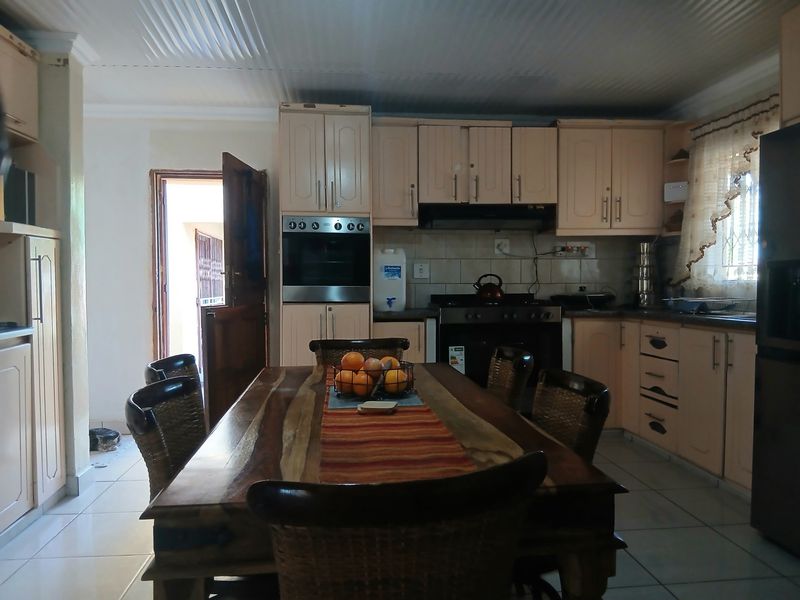 Open-plan kitchen and dining area featuring built-in cabinetry, integrated oven, hob, extractor fan, and tiled flooring.