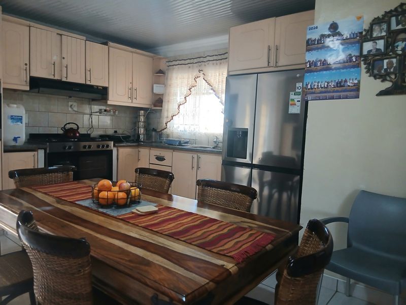 Open plan kitchen and dining area featuring built-in cabinetry, a gas stove with extractor fan, and tiled backsplash.