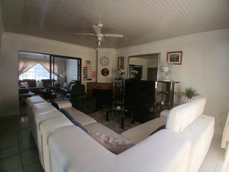 Spacious living room featuring a central fireplace, ceiling fan, and large sliding glass doors that provide natural light and access to an adjacent room.