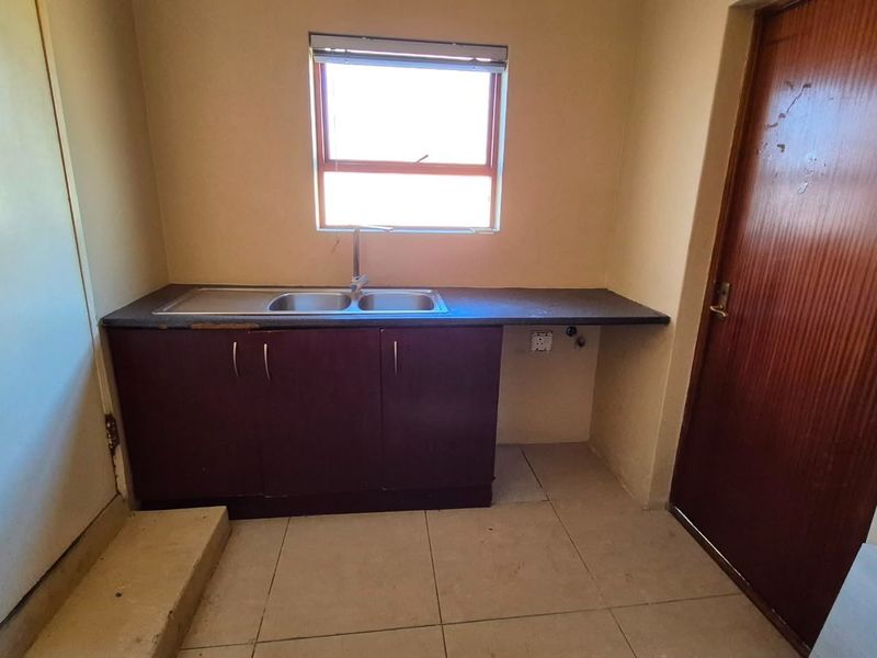 A functional scullery area featuring a double bowl sink, laminate countertop, and base cabinetry, providing a dedicated space for utility and wash-up tasks.
