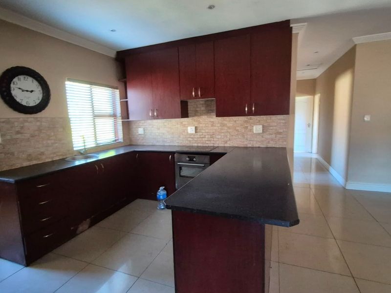 A functional kitchen featuring dark wood cabinetry, stone countertops, built-in oven, and tiled backsplash, offering a clean layout ready for modern updates.